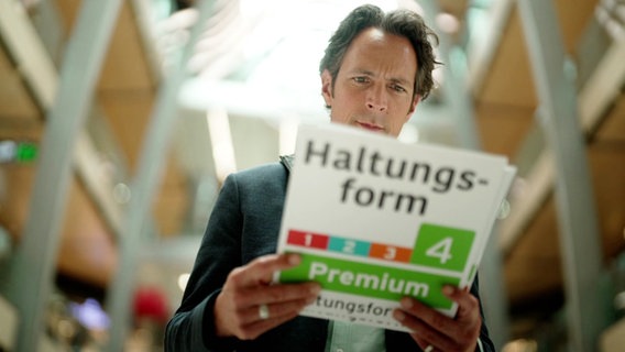 Jo Hiller mit einem überdimensionalen Label "Haltungsform 4 - Premium". © Screenshot 