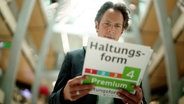 Jo Hiller mit einem überdimensionalen Label "Haltungsform 4 - Premium". © Screenshot 