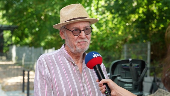 Reinhard, älter, graue Haare, trägt einen Strohut, wird interviewt. © Screenshot 