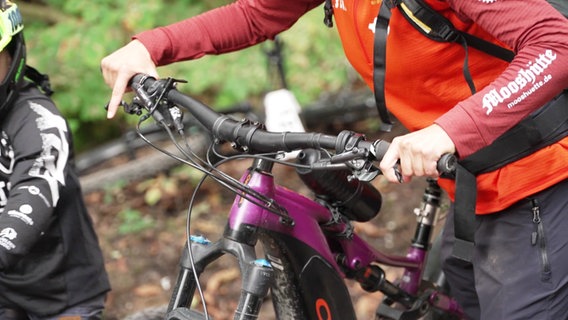 Eine Person hält den Lenker eines Mountainbikes. © Screenshot 