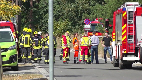 Blick aus der Ferne auf eine Einsatzstelle von Feuerwehr und Rettungsdienst: Viele Einsatzkräfte haben sich für eine Lagebesprechung versammelt. © Screenshot 