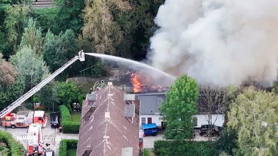 Einsatzkräfte löschen ein Feuer in einer Bootshalle. © Screenshot 