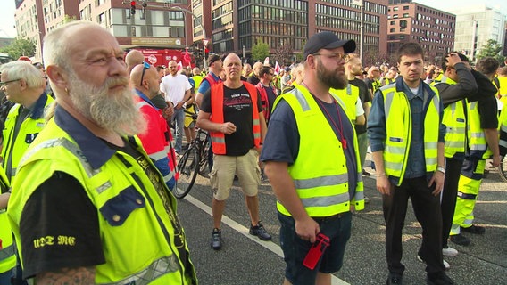 Protestierende Hafenarbeiter stehen in der Hamburger Innenstadt. © Screenshot 