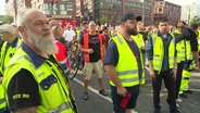 Protestierende Hafenarbeiter stehen in der Hamburger Innenstadt. © Screenshot 