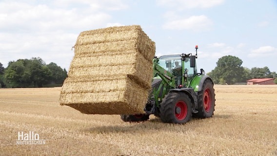 Ein Traktor hat Strohballenauf der Forke. © Screenshot 