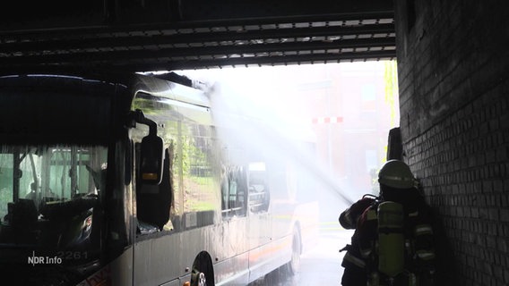 Einsatzkräfte der Feuerwehr löschen einen Bus. © Screenshot 