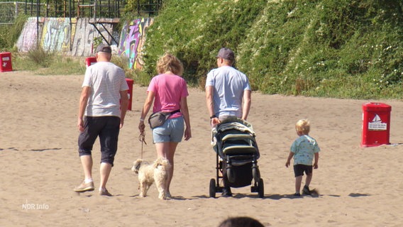 Menschen laufen durch den Sand an einem Strand. © Screenshot 