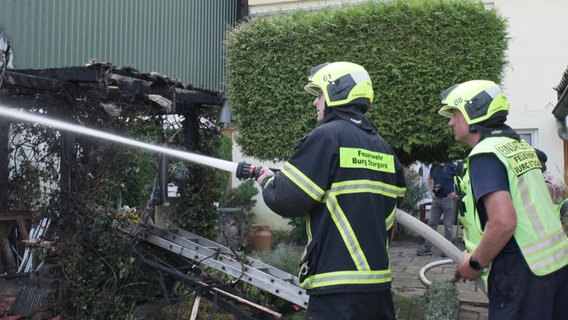 Zwei Feuerwehrmänner richten einen Wasserstrahl auf ein Brandnest. © Screenshot 