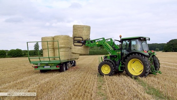 Ein Traktor hebt einen Heuballen auf einen Anhänger. © Screenshot 