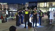 Der Jungfernstieg bei Nacht in Hamburg. Polizisten stehen im Einsatz bei einer Gruppe von Jugendlichen. © Screenshot 