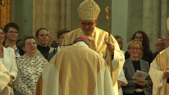 Osnabrücks neuer Bischof Dominicus Meier bekommt den Bischofsstab von seinem Vorgänger Franz-Josef Bode überreicht. © Screenshot 