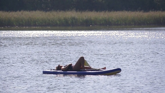 Eine Person sonnt sich auf einem Boot im Wasser. © Screenshot 