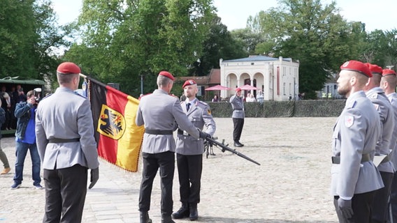 Ein Offizier übergibt eine Flagge. © Screenshot 