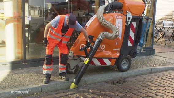 Ein Mann von der Stadtreinigung bedient eine Straßenkehrmaschine mit einem Staubsauger. © Screenshot 