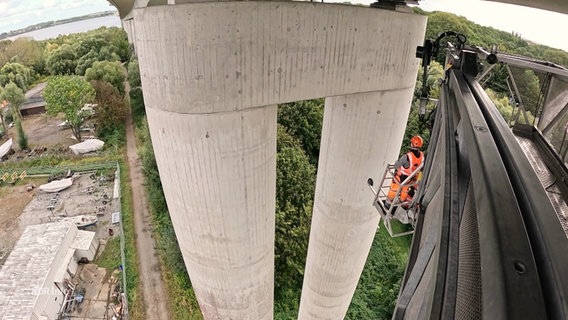 Ein Mann überprüft die Brückenpfeiler der Rügenbrücke. © Screenshot 