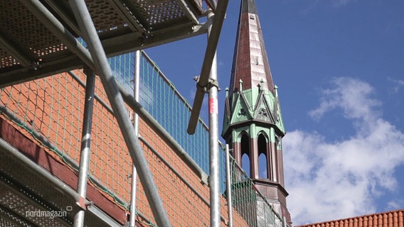 Im Vordergrund ein Baugerüst, im Hintergrund ein Turm der Klosterkirche in Neukloster. © Screenshot 