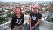 Cora Gutzeit und Dirk Protesta stehen auf ihrem Balkon in der höchsten Etage des Ihme-Zentrums. © Screenshot 