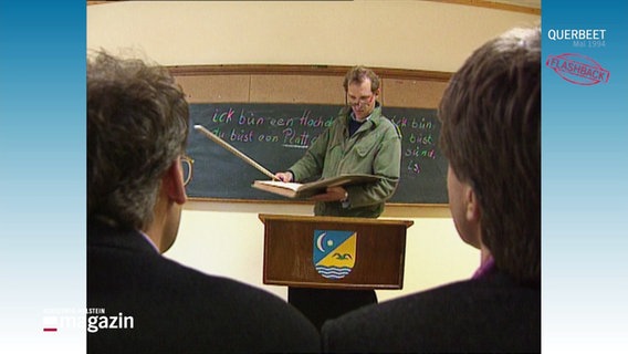 Peter Heinrich Brix unterrichtet vor einer Tafel mit Lehrstock. © Screenshot 