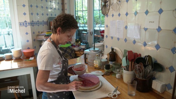 Susanne Dechows steht in ihrer Küche und verstreicht Himbeermasse auf einem Käsekuchen. © Screenshot 