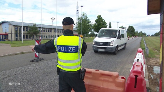 Ein Polizist winkt ein Auto bei einer Grenzkontrolle durch. © Screenshot 