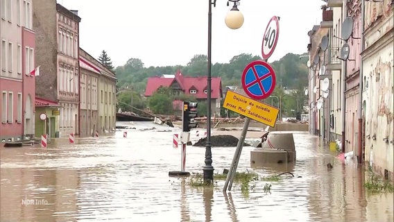 Mehrere Häuser an einer Straße stehen unter Wasser. © Screenshot 