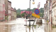 Mehrere Häuser an einer Straße stehen unter Wasser. © Screenshot 