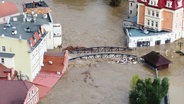 Mehrere Straßen in einem Ort stehen unter Wasser. © Screenshot 