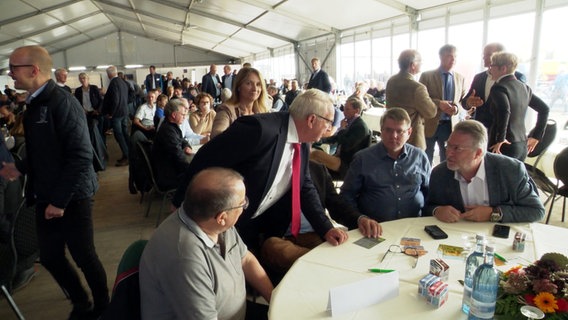 Eine Szene aus der Landwirtschaftsmesse MeLa: Till Backhaus beugt sich über einen Tisch und spricht Thomas Diener an. © Screenshot 