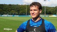 Ein Fußballspieler von Holstein Kiel auf einem Spielfeld. © Screenshot 