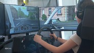 Eine Fahrschülerin trainiert an einem Simulator. © Screenshot 