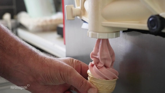 Eine Hand zapft eine rosa Softeis-Portion in eine Eiswaffel. © Screenshot 