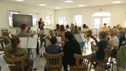 Viele Kinder sitzen im Orchester bei der Probe. © Screenshot 