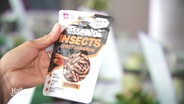 Eine Snack-Packung in einer Hand: "Insects - Sweet cinnamon". © Screenshot 