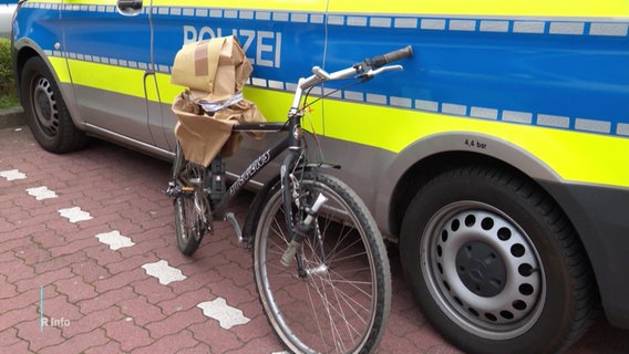 Ein kaputtes Fahrrad lehnt an einem Polizeifahrzeug. © Screenshot 