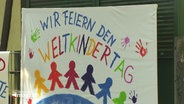 "Wir feiern den Weltkindertag", steht auf einem farbigen Banner geschrieben. © Screenshot 