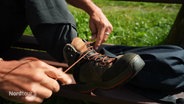 Jemand schnürt seine Wanderschuhe. © Screenshot 