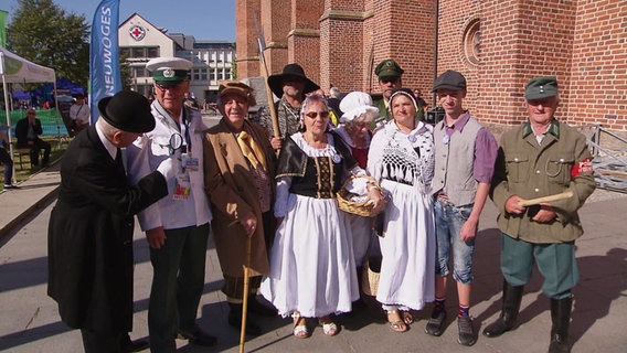 Eine Gruppe von Menschen in unterschiedlichen Kostümen. © Screenshot 