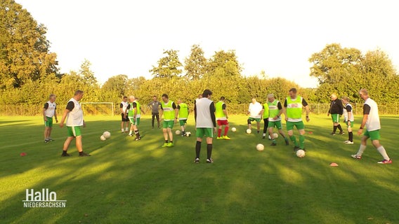 Beim Fußballtraining kicken sich Menschen Bälle zu. © Screenshot 