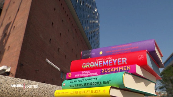 Ein Stapel Bücher liegt auf dem Boden vor der Elbphilharmonie. © Screenshot 