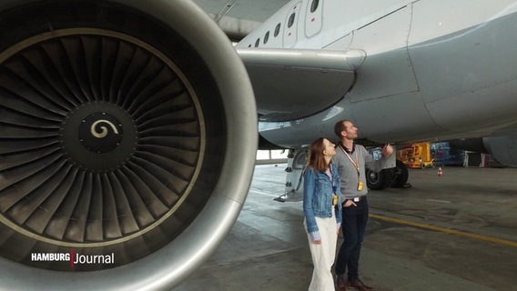 Zwei Personen laufen an einem Lufthansa Flugzeug vorbei. © Screenshot 