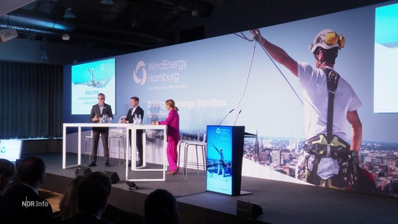 Drei Personen stehen bei der Eröffnung der Messe "WindEnergy" auf einer Bühne. © Screenshot 