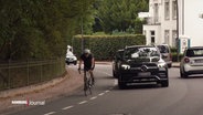 Ein Radfahrer auf einem Fahrradstreifen am Rande einer Straße wird von einem Auto überholt. © Screenshot 