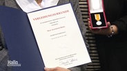 Den Angehörigen einer getöteten Frau werden stellvertretend Urkunde und Medaille für ihre Zivilcourage überreicht. © Screenshot 