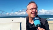 Sylts Bürgermeister Nikolas Häckel steht an einem Strandkorb und wird vom NDR interviewt. © Screenshot 