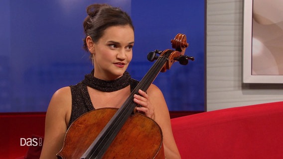 Raphaela Gromes sitzt mit ihrem Cello auf dem roten Sofa. © Screenshot 