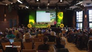 Viele Delegierte sitzen beim Hamburger Landesparteitag der Grünen in einem Saal. © Screenshot 