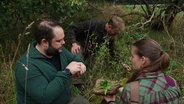 Mehrere Menschen sitzen in einem Wald. © Screenshot 