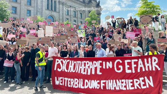 Auf einer Demo wird ein Banner mit der Aufschrift: "Psychotherapie in Gefahr - Weiterbildung finanzieren" getragen. © Screenshot 