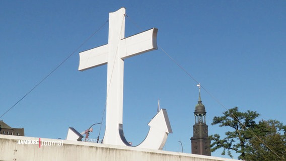 Ein großes weißes Kreuz, das in einen Anker übergeht. © Screenshot 