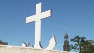 Ein großes weißes Kreuz, das in einen Anker übergeht. © Screenshot 